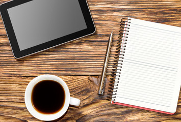 Tablet pc, notepad and cup of coffee on the table. Business conc