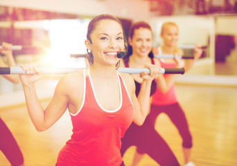 group of smiling people working out with barbells