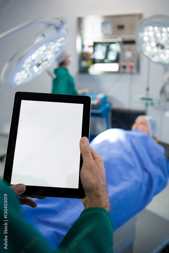 Poster Surgeon using digital tablet while operating patient