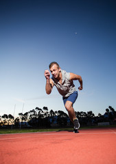 Male sprinter athlete on a tartan athletic track getting ready f