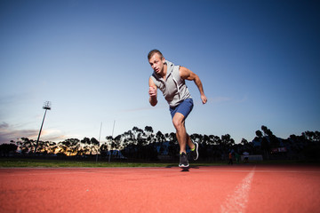 Male sprinter athlete on a tartan athletic track getting ready f