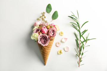 Waffle cone with composition of flowers and branches on white background
