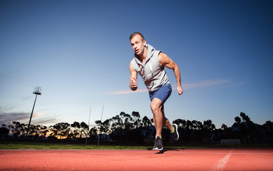 Male sprinter athlete on a tartan athletic track getting ready f