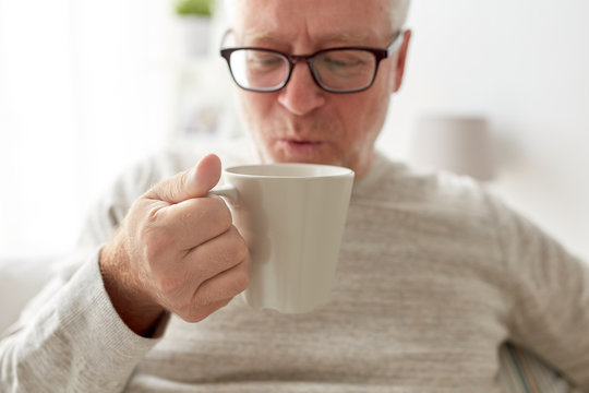 happy senior man drinking tea or coffee at home