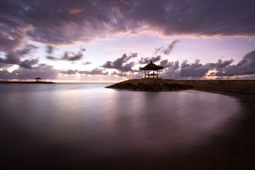Obraz premium Balinese beach at sunrise with a little temple. Indonesia.