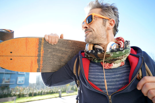 Skateboarder in town holding skateboard on shoulder