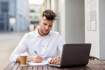 man with laptop and coffee at city cafe