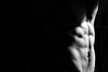 Male fitness model showing muscles in studio with a black backgr