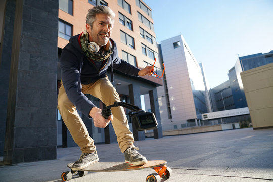 Mature man skateboarding in urban environment, filming himself