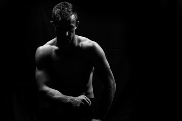 Obraz na płótnie Canvas Male fitness model showing muscles in studio with a black backgr