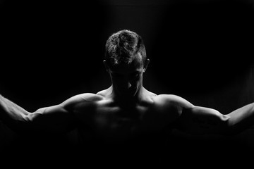 Fototapeta na wymiar Male fitness model showing muscles in studio with a black backgr