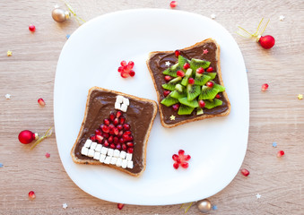 Chocolate sandwich with marshmallow and pomegranate Santa Claus hat and kiwi Christmas tree - creative idea for kids breakfast, dessert or holiday meal, top view flat lay, blank space for text