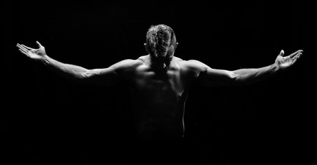 Fototapeta na wymiar Male fitness model showing muscles in studio with a black backgr