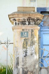Hausnummer 34 auf verwitterter Steinsäule vor historischem Gebäude im Sonnenlicht