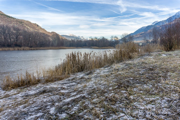park with a frozen lake in the winter and mountains background