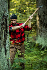 portrait of a man - lumberjack with an ax in the forest, front view