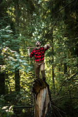 portrait of a man - lumberjack with an ax in the forest, front view