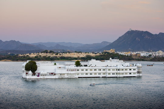 The Lake Palace Hotel, Jag Niwas, on island site on Lake Pichola in early morning with tourist boat leaving, Udaipur, Rajasthan