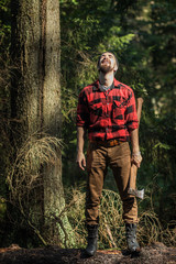 portrait of a man - lumberjack with an ax in the forest, front view