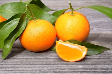 tangerines, peeled tangerine and tangerine slices on a white wooden table