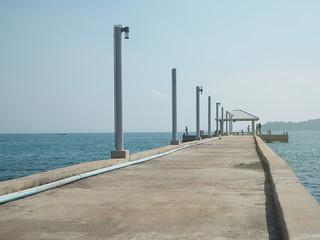 concrete pier on sea/ocean with blue sky background in Thailand.