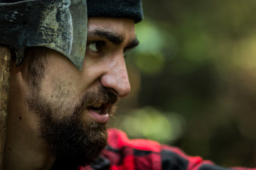 portrait of a man - lumberjack with an ax in the forest, side view