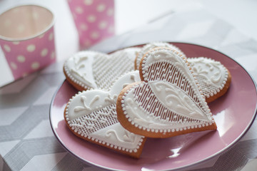 White gingerbread in the shape of a heart on a pink plate for valentine's day
