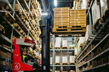 young man in working clothes, driver Reachtruck busy working on the logistics warehouse store