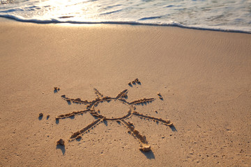 petit soleil dessiné sur le sable à la mer