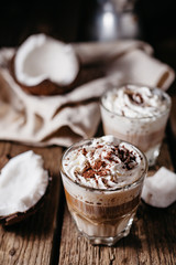 Coconut latte on a wooden table. Broken coconut. Low key food photo.