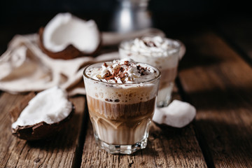 Coconut latte on a wooden table. Broken coconut. Low key food photo.