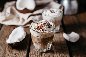 Coconut latte on a wooden table. Broken coconut. Low key food photo.