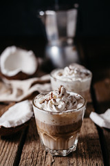 Coconut latte on a wooden table. Broken coconut. Low key food photo.