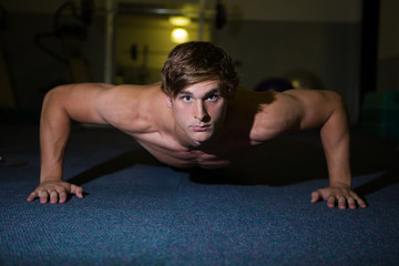 Fototapeta premium A Good looking male model flexing his muscles in a gym using wei