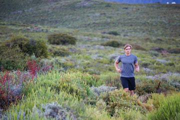 Naklejka na ściany i meble Male fitness model running allong a trail in the field, wearing