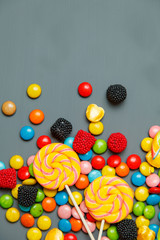 Colorful lollipops, candy canes and sweet candies mix on gray wooden background