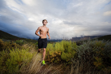 Naklejka na ściany i meble Male fitness model running allong a trail in the field, bare che