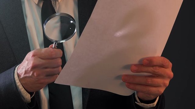 Tax inspector looking at corporate financial documents with magnifying glass
