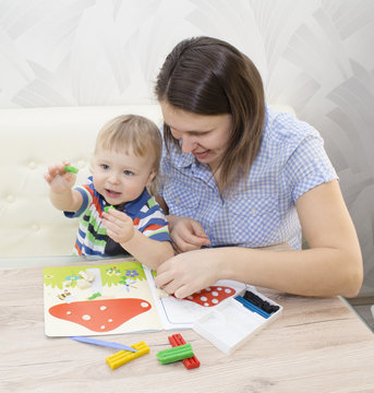 Young pretty woman and child boy playing with colorful clay in nursery