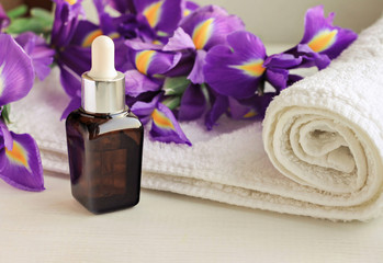 Obraz na płótnie Canvas Flower essence dropper bottle,violet Iris, white terry towel wrap.Floral decorated spa set. Warm toned.