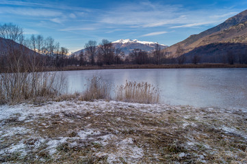 mountains, sky and clouds reflected in the lake on cold winter season