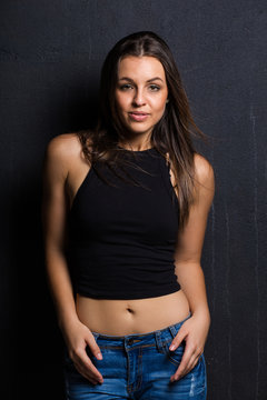 Sexy brunette model on a studio against a dark wall