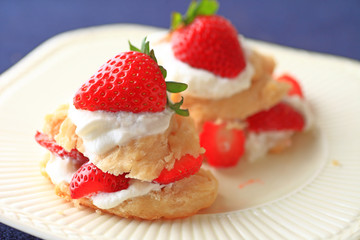Miniature strawberry shortcakes with whipped cream and fresh berries on a white dish