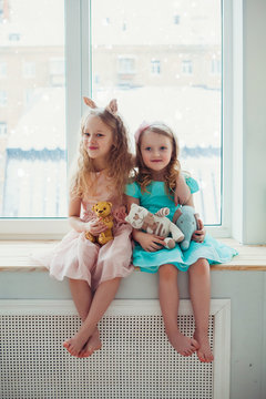 Cute little girls sitting by the window.