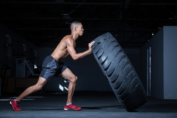 Personal trainer doing a tyre flip in a gym