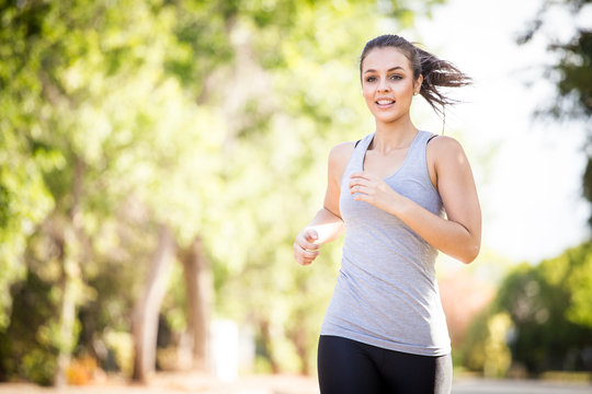 Close up image of a female fitness model running / exercising in a street in a suburban area