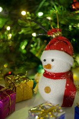 snowman with blurry christmas tree background and light bokeh