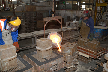A founder pours molten iron in a mould