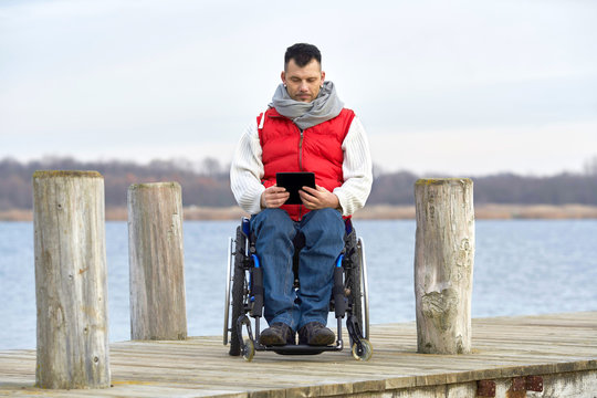junger Mann im Rollstuhl mit seinem Tablet - Computer