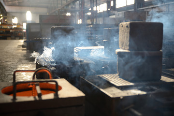 steam rises as cast iron cools in a foundry